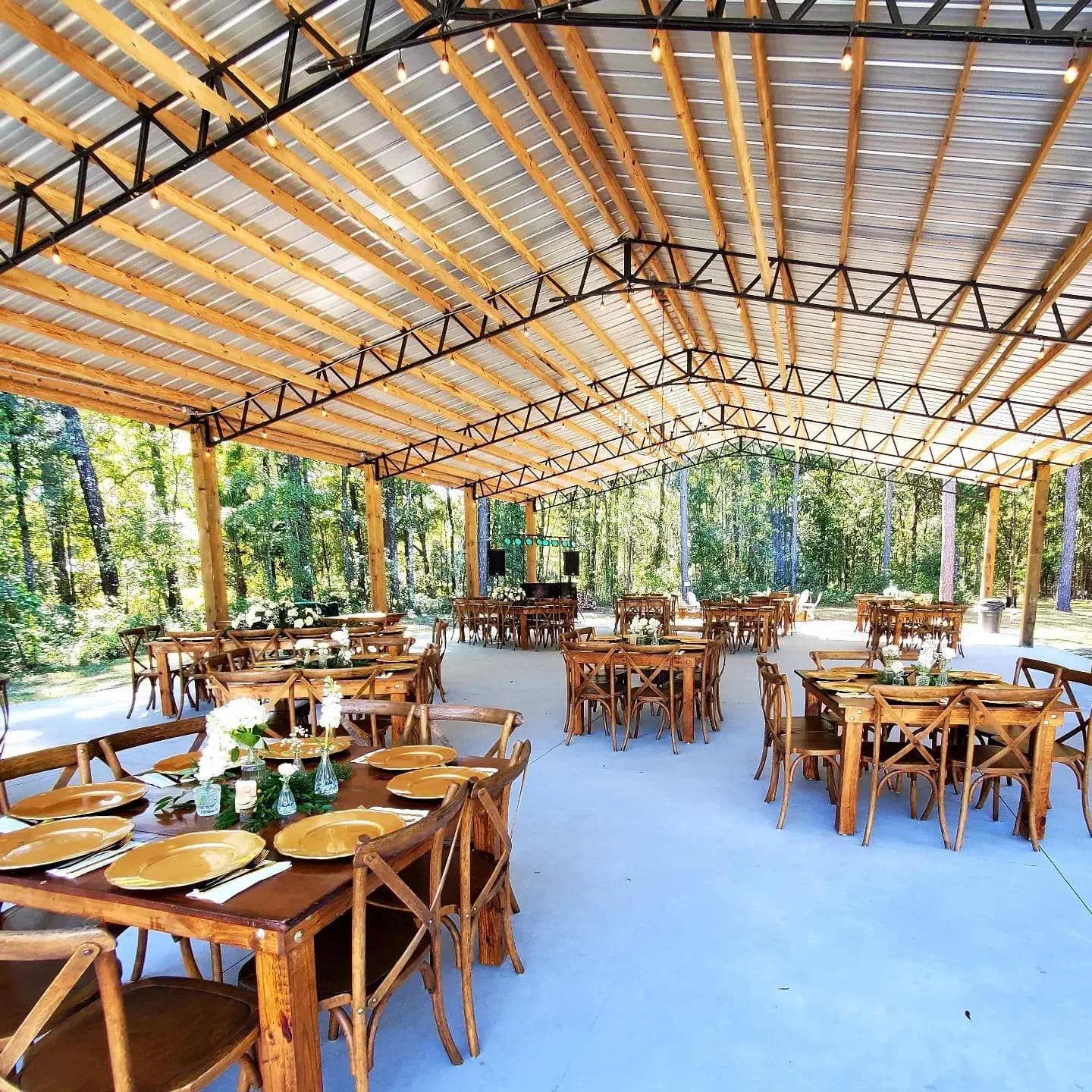 Long wooden farm tables set with greenery down the middle of the pavilion